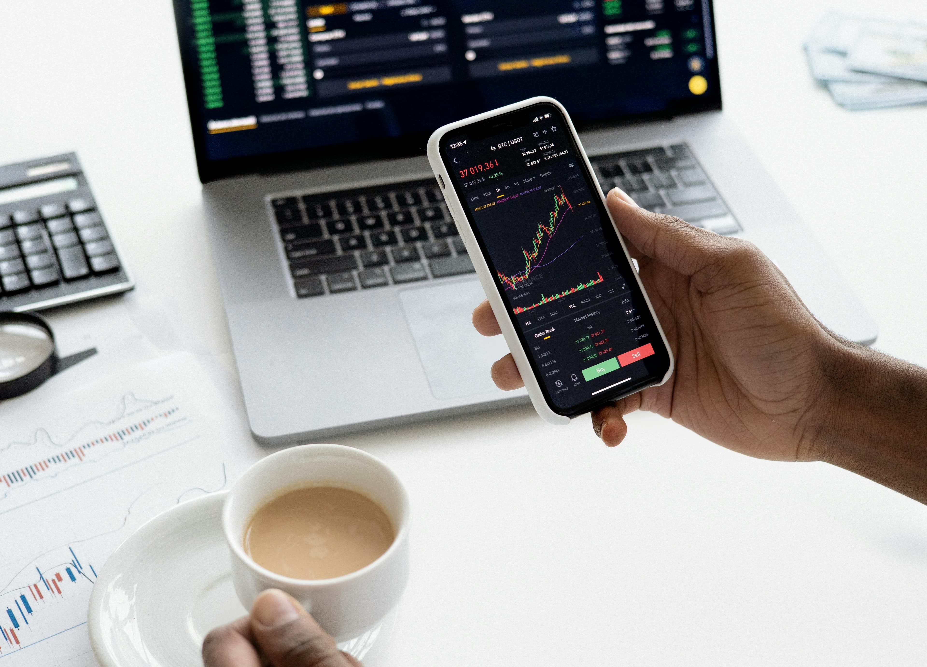 Українець вивчає криптовалютні інвестиції на смартфоні з графіками Bitcoin та Ethereum